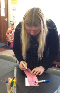 One of ATS craft group writing on her pink odd sock. with different colour fabric markers.