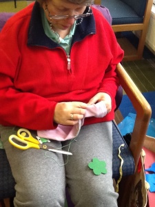 ATS craft group member blanket stitching around her green flower with green cotton onto one side of the sock.